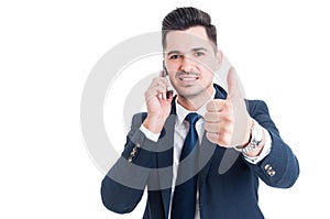 Young successful businessman talking on smartphone and showing t