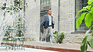 A young successful businessman is walking down the street. Man in a casual wear. Business, freelance and remote work.