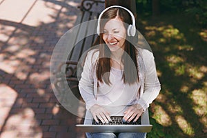 Young successful businesswoman in light casual clothes. Woman working on modern laptop pc computer, listen music in