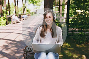 Young successful businesswoman in light casual clothes. Woman working on modern laptop pc computer, listen music in