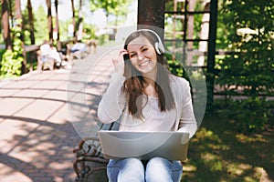 Young successful businesswoman in light casual clothes. Woman working on modern laptop pc computer, listen music in