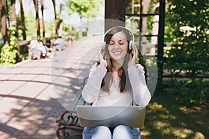 Young successful businesswoman in light casual clothes. Woman working on modern laptop pc computer, listen music in