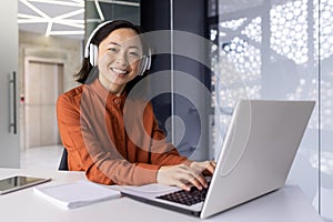 Young successful female programmer at workplace inside office working with laptop, coding software, smiling and looking