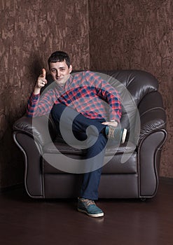 Young successful guy sitting on a leather armchair.