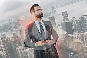 Young and successful. Handsome bearded businessman in full suit adjusting his jacket and looking away while standing
