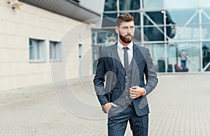 Young and successful. Handsome young man in full suit adjusting his jacket while standing outdoors