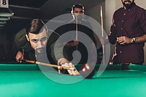 young successful handsome man playing in russian pool at bar