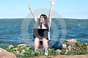 Young successful happy girl on the beach uses a laptop for work. Freelance work concept, Freelancer and blogger outside