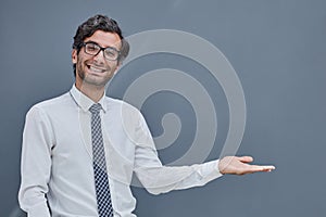 young successful man on a gray background points his fingers to the side