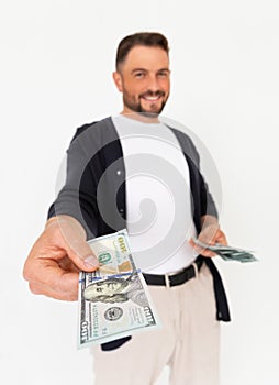 Young successful man holding out his hand with a 100 dollar bill on a white background