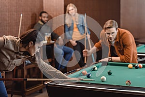 young successful multiethnic friends playing in pool