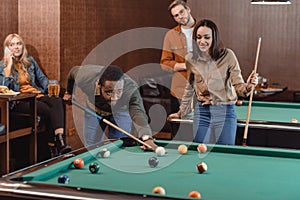 young successful multiethnic friends playing in pool