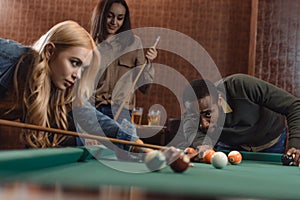 young successful multiethnic friends playing in pool