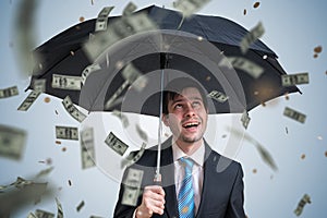 Young successful rich businessman with umbrella and money falling down.