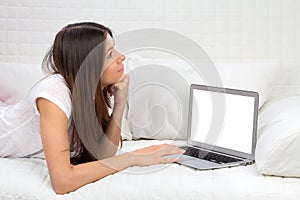 Young successful woman lying on a sofa with laptop paying bills