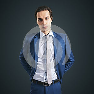 Young successfull businessman in suit and grey tie on black background, close up