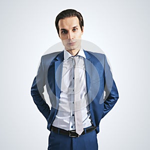 Young successfull businessman in suit and grey tie on light background, close up