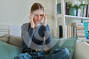 Young suffering female having headache, sitting on couch at home