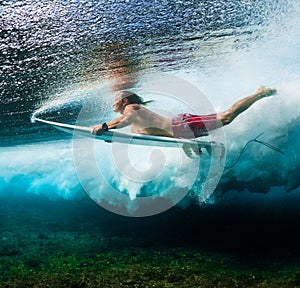 Young surfer dives under the ocean wave