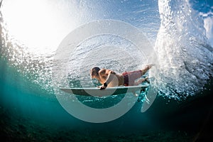 Young surfer dives under the ocean wave