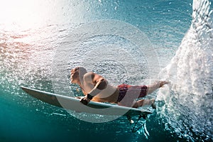 Young surfer dives under the ocean wave