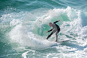 Young surfer enjoys the waves confronting the surf by surfing the rougher waters after a morning rain storm