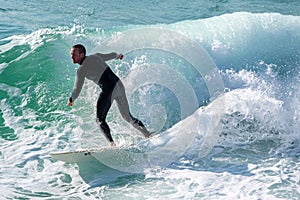 Young surfer enjoys the waves confronting the surf by surfing the rougher waters after a morning rain storm