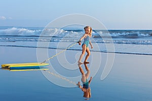 Young surfer girl with bodyboard walks along beach sea surf