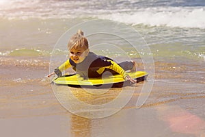 Young surfer girl with bodyboard walks along beach sea surf