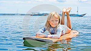 Young surfer girl lying on surfboard