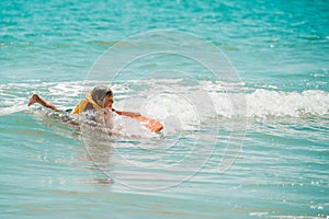 Young surfer, happy young girl in the ocean on surfboard. Kid learn to surf with board.