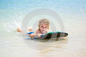 Young surfer, happy young boy in the ocean on surfboard.