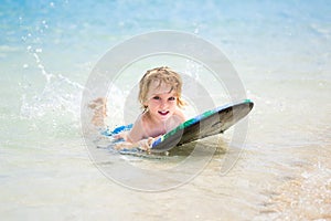 Young surfer, happy young boy in the ocean on surfboard.