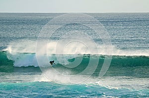 Young surfer riding on the breaking waves in Pacific Ocean at Hanga Roa, Easter Island, Chile