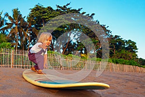 Young surfer stand on surfboard with fun on sunset beach