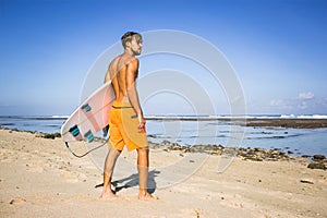 young surfer with surfing board standing on sandy beach