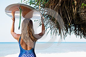 Young surfer woman with surfboard walk on beach