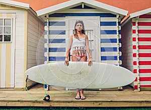 Young surfer woman with top and bikini holding