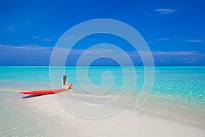 Young surfer woman at white beach on red surfboard