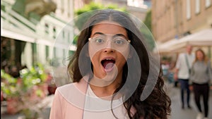Young surprised amazed excited woman Indian Arabian female girl outside. Positive businesswoman shock smiling open mouth