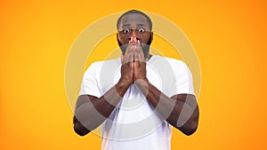 Young surprised black man closing his mouth with hands on yellow background