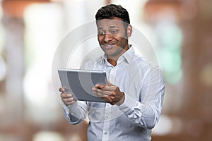 Young surprised businessman looking at digital tablet pc.
