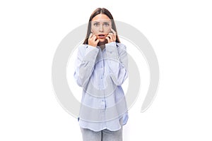 young surprised european business lady with long black hair dressed in a blue blouse on a white background with copy