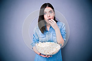 Young surprised woman eating popcorn