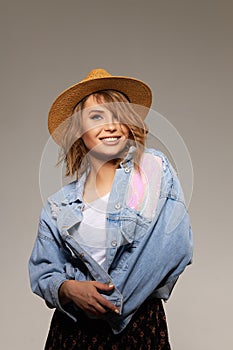 Young surprised woman model in a fashionable hat and denim jacket on a gray background.