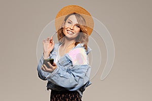 Young surprised woman model in a fashionable hat and denim jacket on a gray background.