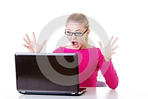 Young surprised woman sitting in front of laptop.