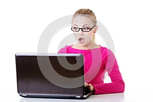 Young surprised woman sitting in front of laptop.