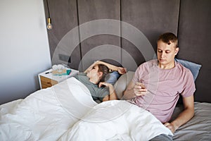 Young suspicious man reading messages in his wife smartphone