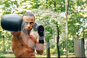 Young sweated boxer performing shadow boxing